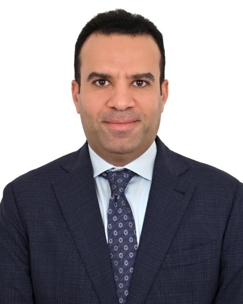 Hossam Abo El-Fottoh- Professional headshot of a man in a dark suit and patterned tie, smiling against a plain light background.